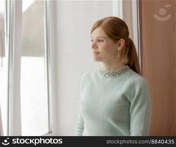 beautiful woman of middle age looking to the window. Red hair woman wearing mint color sweater.. beautiful woman of middle age looking to the window. 
