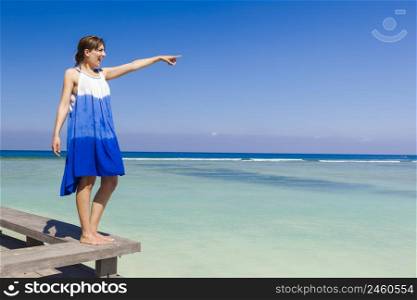 Beautiful woman on a beautiful tropical beach pointing to somewhere