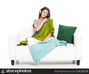 Beautiful woman on a sofa and listen music, isolated in white