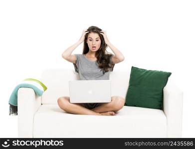 Beautiful woman on a sofa astonished with something in the laptop, isolated in white