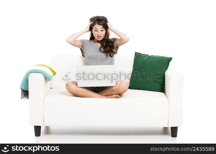 Beautiful woman on a sofa astonished with something in the laptop, isolated in white