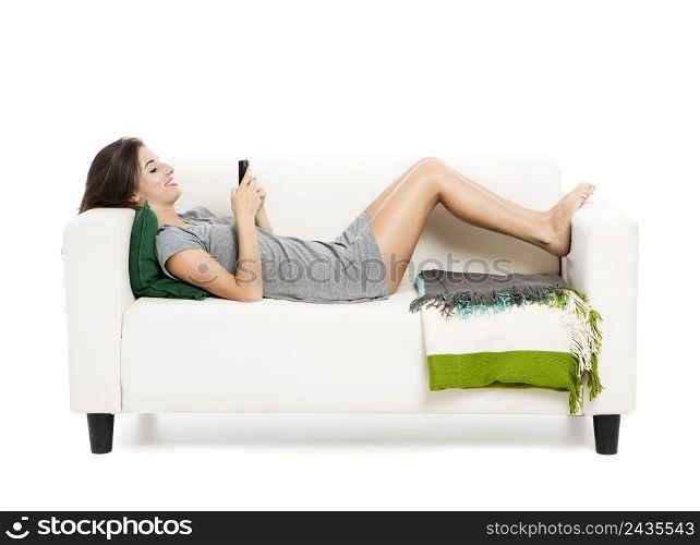 Beautiful woman on a sofa drinking tea, isolated over a white background