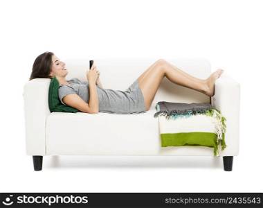 Beautiful woman on a sofa drinking tea, isolated over a white background