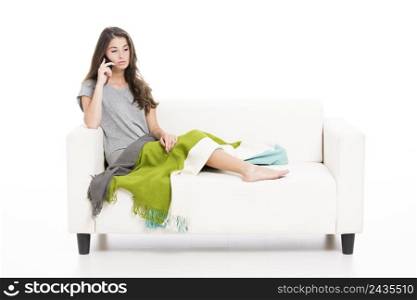 Beautiful woman on a sofa talking at cellphone, isolated over a white background