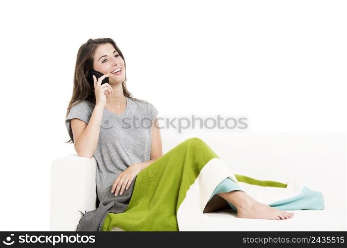 Beautiful woman on a sofa talking at cellphone, isolated over a white background