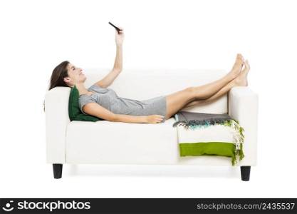 Beautiful woman on a sofa with a cellphone texting, isolated in white