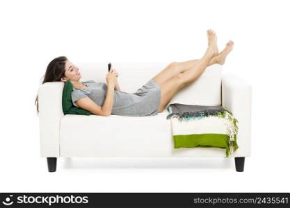 Beautiful woman on a sofa with a cellphone texting, isolated in white