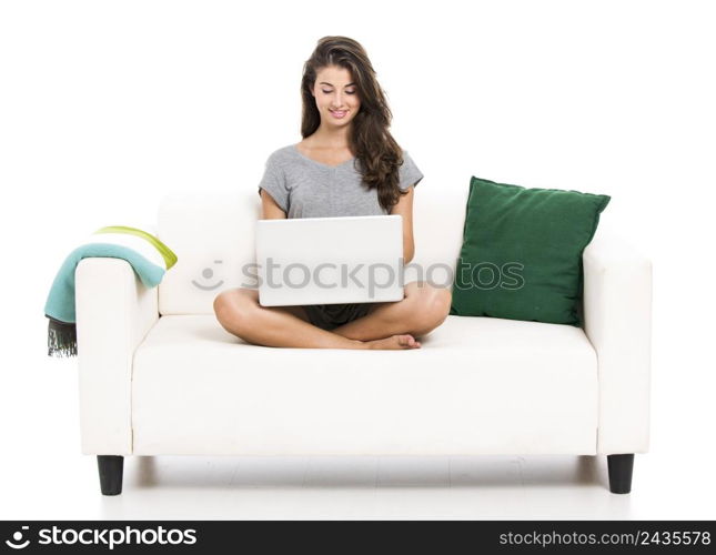 Beautiful woman on a sofa working with a laptop, isolated in white