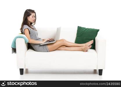Beautiful woman on a sofa working with a laptop, isolated in white
