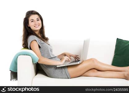 Beautiful woman on a sofa working with a laptop, isolated in white