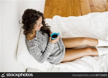 Beautiful woman on bed drinking a coffee