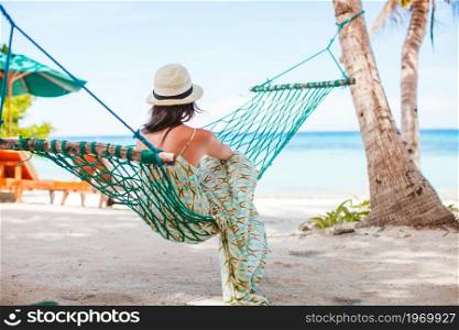 Beautiful woman on summer vacation relaxing in hammock. Adorable girl on tropical vacation relaxing in hammock