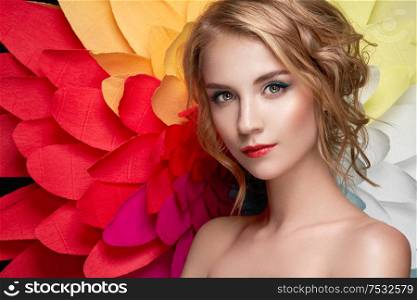 Beautiful woman on the background of a large flower. Beauty summer model girl with rainbow chrysanthemum. Young woman with elegant hairstyle and makeup. Fashion photo