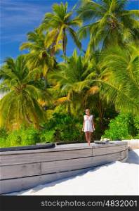 Beautiful woman on tropical beach, walking along boardwalk on luxury exotic resort, enjoying summer vacation on Maldives&#xA;