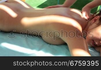 Beautiful woman outdoor receiving a back massage at spa resort