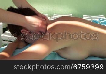 Beautiful woman outdoor receiving a back massage at spa resort.