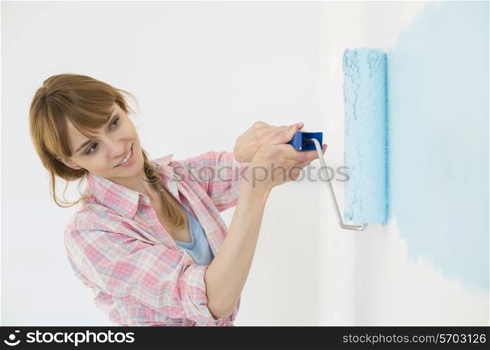Beautiful woman painting wall with paint roller