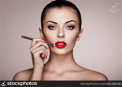 Beautiful woman paints lips with lipstick. Beautiful woman face. Makeup detail. Beauty girl with perfect skin