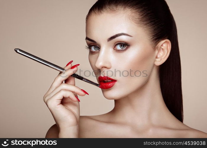 Beautiful woman paints lips with lipstick. Beautiful woman face. Makeup detail. Beauty girl with perfect skin