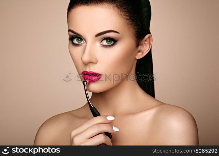 Beautiful woman paints lips with lipstick. Beautiful woman face. Makeup detail. Beauty girl with perfect skin. Red lips and nails manicure