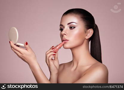 Beautiful woman paints lips with lipstick. Beautiful Woman Paints Lips with Lipstick. Beautiful Woman Face. Makeup Detail. Beauty Lady with Perfect Skin. Lips and Nails Manicure. Make-up Artist