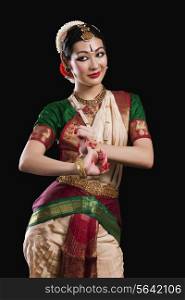 Beautiful woman performing Bharatanatyam on black background