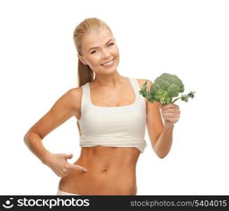 beautiful woman pointing at her abs and holding broccoli