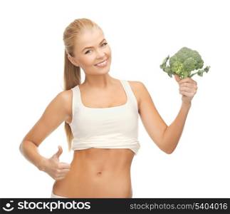 beautiful woman pointing at her abs and holding broccoli