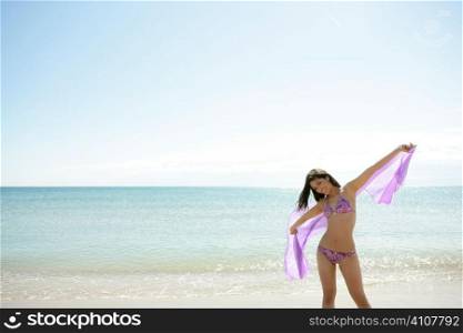 beautiful woman posing in bikini on the beach playing with the wind