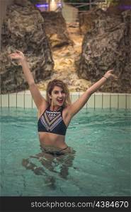 Beautiful woman posing in the swimming pool wearing a fashion swimwear