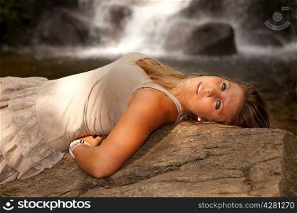 Beautiful woman posing near a waterfall
