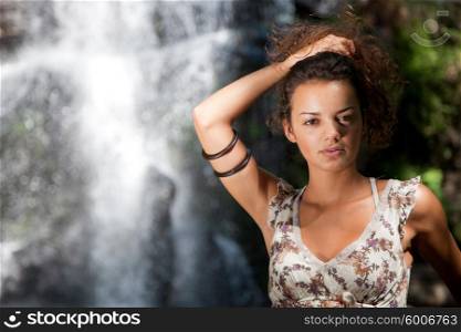 Beautiful woman posing near a waterfall