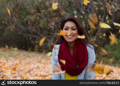 Beautiful woman posing outdoors during autumn among the falling leaves