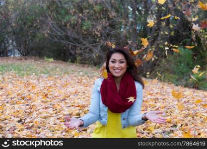 Beautiful woman posing outdoors during fall among the falling leaves