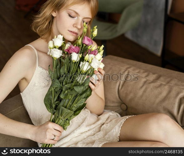 beautiful woman posing sofa while holding bouquet delicate spring flowers