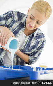 Beautiful woman pouring paint in container