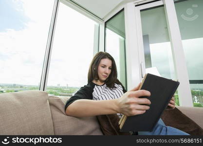 Beautiful woman reading book on sofa at home