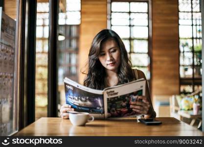 Beautiful woman reading magazine in cafe