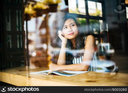 Beautiful woman reading magazine in cafe