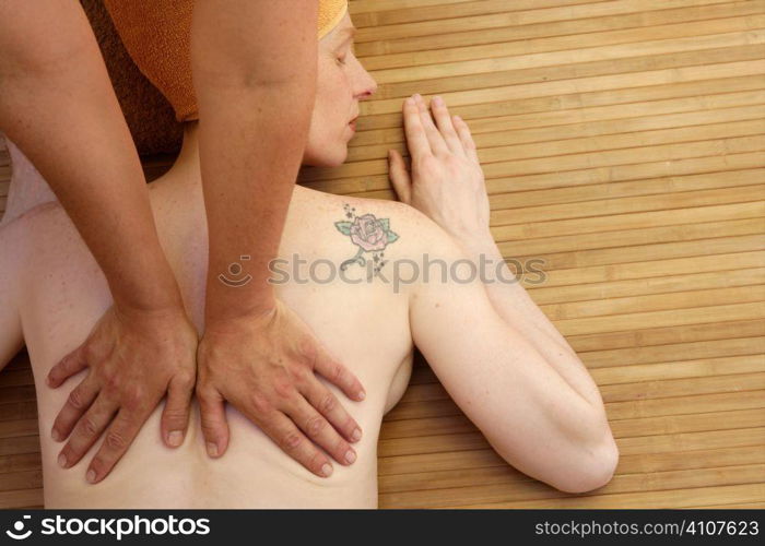 Beautiful woman receiving a back massage over bamboo spa