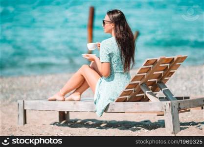 Beautiful woman relax during exotic vacation on the beach enjoying sweet coffee. Young woman with cup of hot coffee enjoy holidays