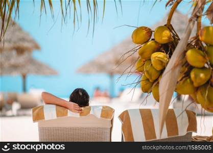 Beautiful woman relax on the beach near big coconuts. Relaxed young women lying on beach lounger near coconut tree