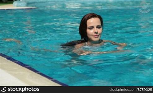 Beautiful woman relaxing in a pool at summer resort