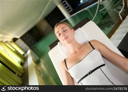 Beautiful woman relaxing in longchair by pool
