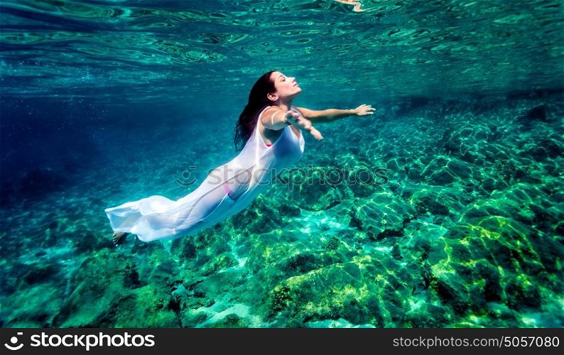 Beautiful woman relaxing in the water, active traveler swimming underwater, enjoying freedom and peaceful undersea nature, pleasure and enjoyment concept