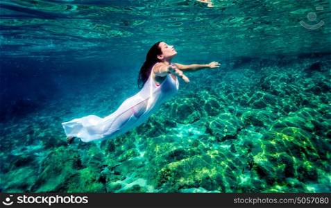 Beautiful woman relaxing in the water, active traveler swimming underwater, enjoying freedom and peaceful undersea nature, pleasure and enjoyment concept