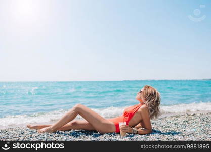 Beautiful woman relaxing on the beach at summer vacation. Outdoor portrait of woman on the beach.