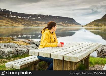 Beautiful woman resting close to a beautiful lake and drinkign a tea
