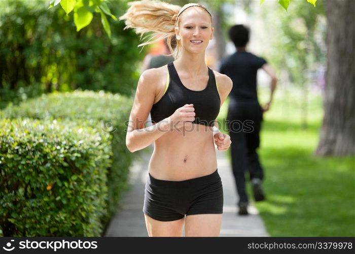 Beautiful woman running in park with people in the background