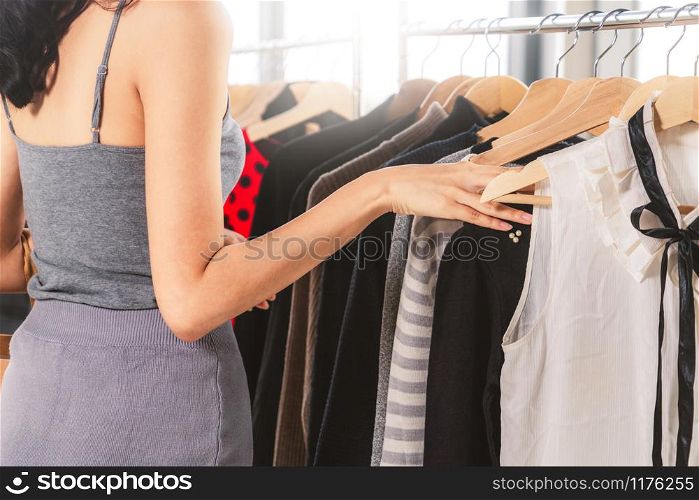 Beautiful woman shopping for clothes at retail apparel shop in the shopping mall. Modern trade lifestyle.